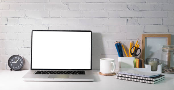 istock Home office desk with laptop, coffee cup, picture frame and stationery on white table. 1437136904