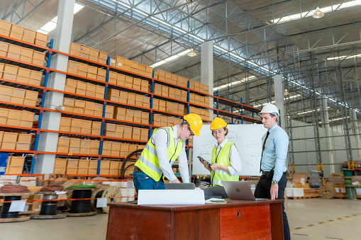 Engineers, employees, businessmen talking in large warehouses, Group of diversity warehouse worker meeting and checking list inventory in industry factory.