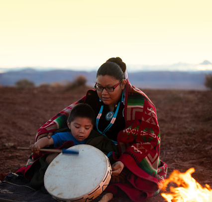 Navajo young woman with little brother around campfire in the Arizona desert
