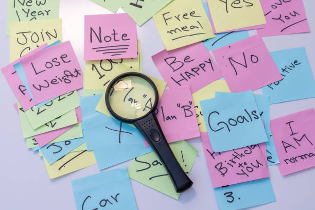 istock New year goals and resolutions hand written on a sticky notes searching with magnifying glass for target to achieve 1437164557