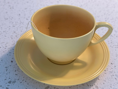 Close up one transparent glass cup of green oolong or herbal tea on saucer isolated on white background, low angle side view