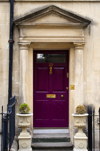 Entrance with purple wooden door and fence at famous City of Bath on a cloudy summer day. Photo taken August 2nd, 2022, Bath, United Kingdom.