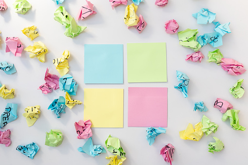 Blank sticky notes with crumbled paper balls on white isolated background