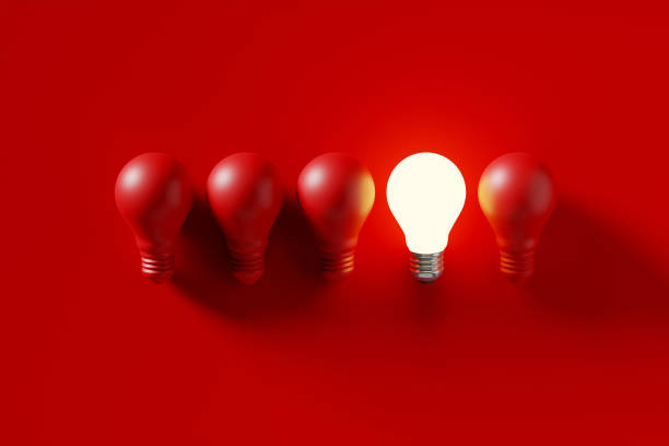 istock Light bulbs in a row with one glowing light bulb amongst the unlit red bulbs 1437176921