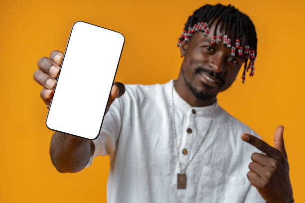 istock Excited young african man holding smartphone with white blank screen in hand on yellow studio background 1437176940