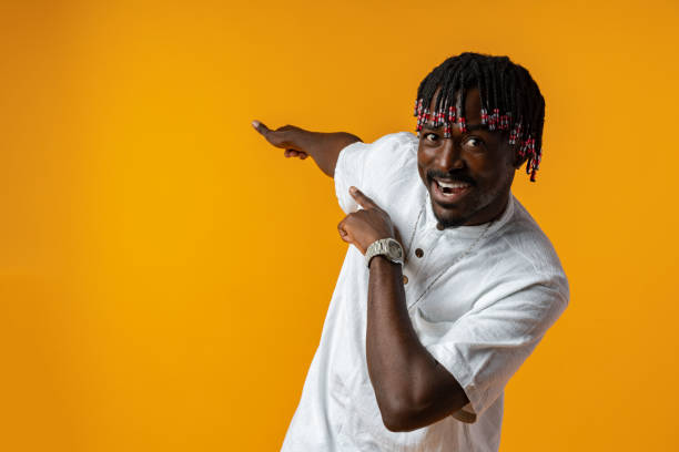 istock African man pointing away to side with finger over yellow background 1437178198