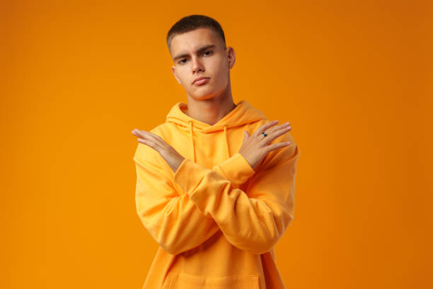 istock Handsome young man over yellow background crossing arms doing negative sign 1437178403