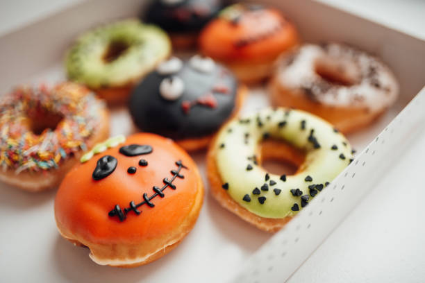 istock Assortment of halloween monsters with funny faces donuts in box at home interior 1437179941