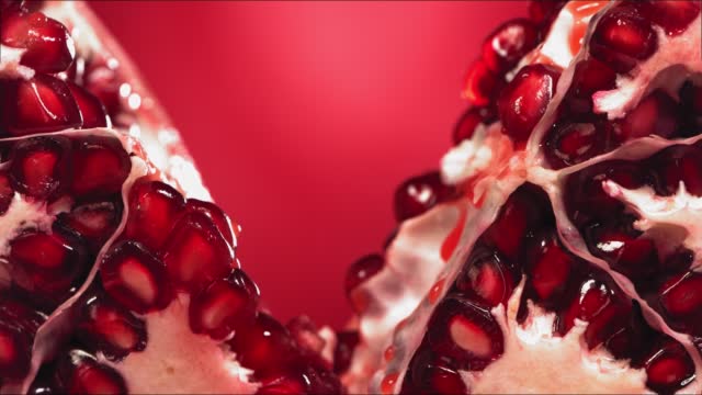 Pomegranate Splits in half and Grains rolls down with juise splash in slow motion
