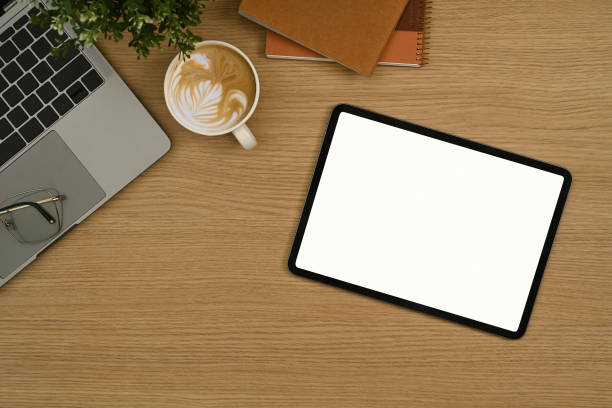 istock Flat lay digital tablet with empty display, coffee cup, laptop and notebook on wooden office desk. 1437192191