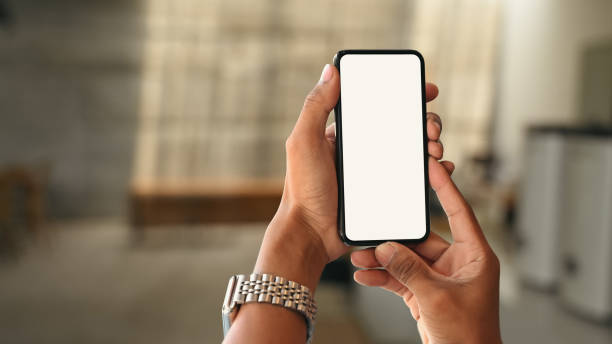 istock Hands holding smart phone over blurred bedroom background. White empty screen for your advertise design. 1437192345
