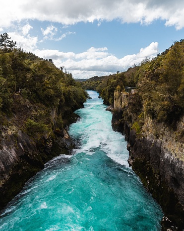 An aerial view of foamy Huka Falls waterfall flowing through cliffs on Waikato River in New Zealand
