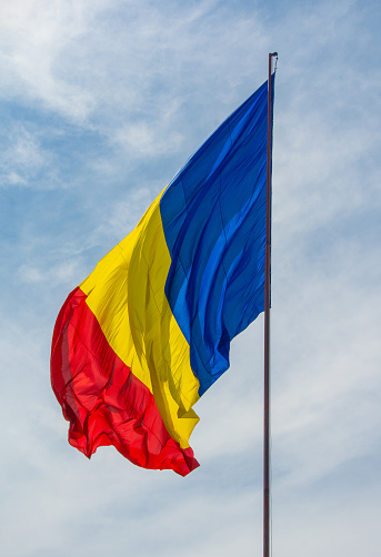 A c\low angle shot of Romania flag on a cloudy sky background