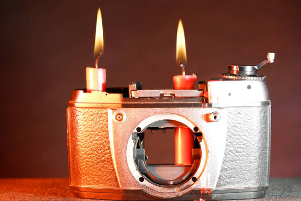 istock Closeup of an old broken camera with burning candles on it on a blurry background 1437197238