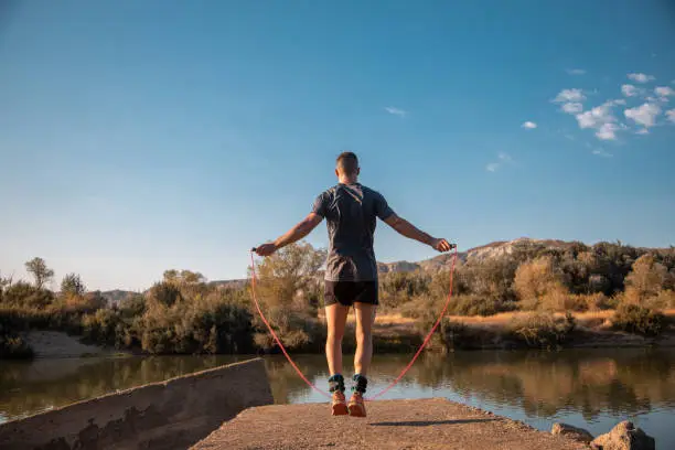 A male training with a jumping-rope next to the river