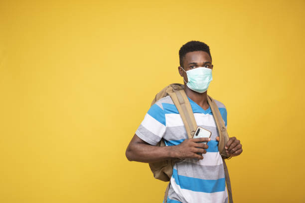 istock Young African male with a backpack wearing a facemask - COVID-19 1437197911