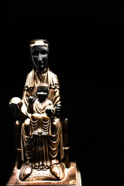 Photo of Vertical shot of a Virgin of Montserrat statue isolated on black background