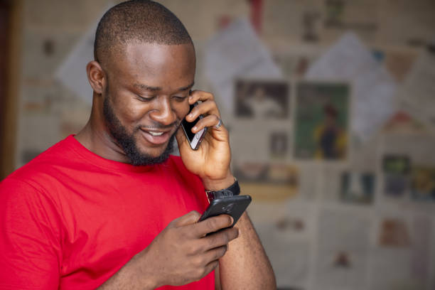 istock Young African male talking on the phone while using another one in a room 1437198605