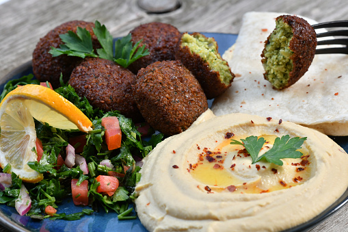 A closeup shot of traditional homemade falafel with different vegetables and hummus