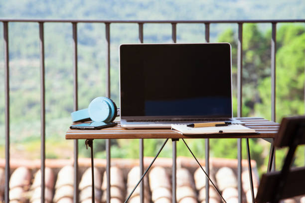 istock Laptop, blue headsets, a notebook, and a cellphone on the table on a balcony with a beautiful view 1437199907