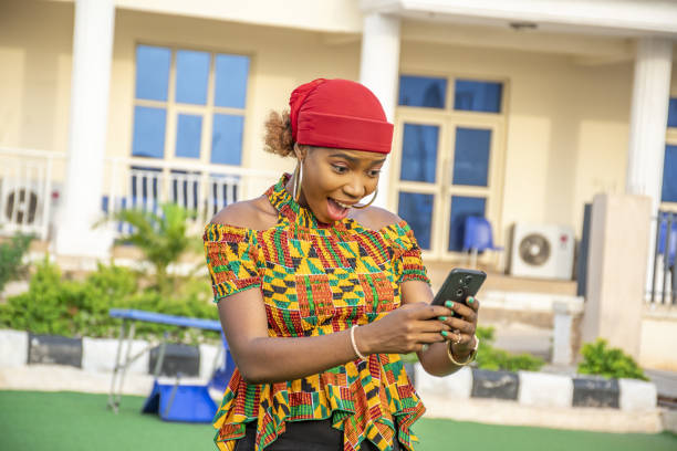 istock pretty young african lady holding her phone, feeling excited 1437200465