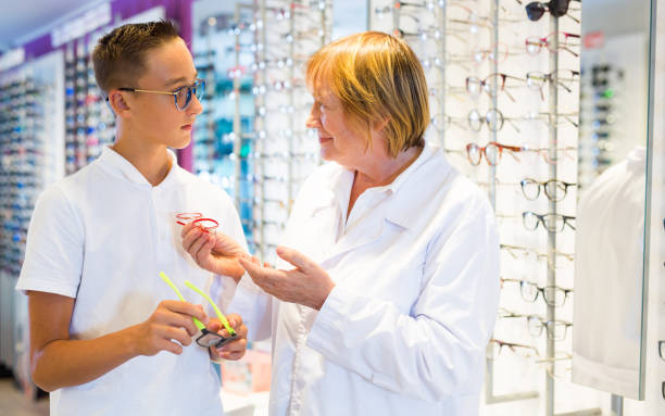 istock Mature female optician helping client to choose a spectacles 1437201557