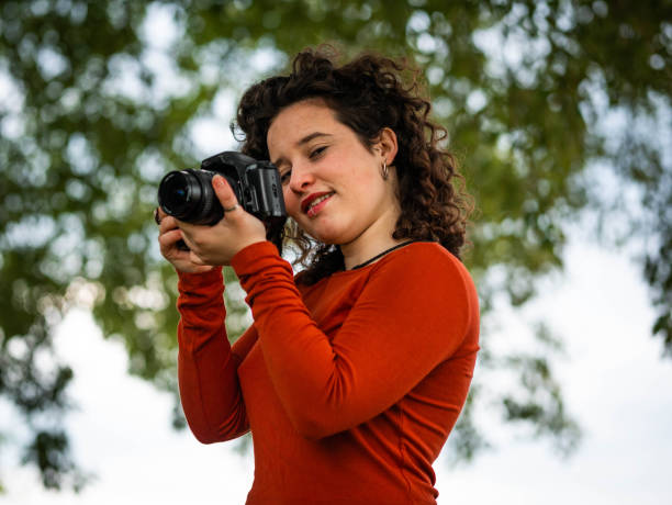 istock Curly Caucasian woman holding a camera during an outdoors shooting 1437201820