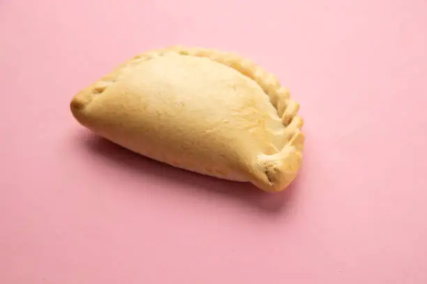 A delicious empanada isolated on pink background