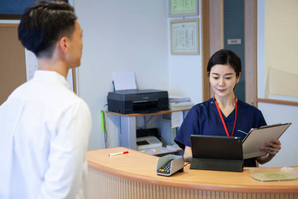 contabilidad de pacientes masculinos en la recepción de la clínica - healthcare and medicine receptionist paying credit card fotografías e imágenes de stock