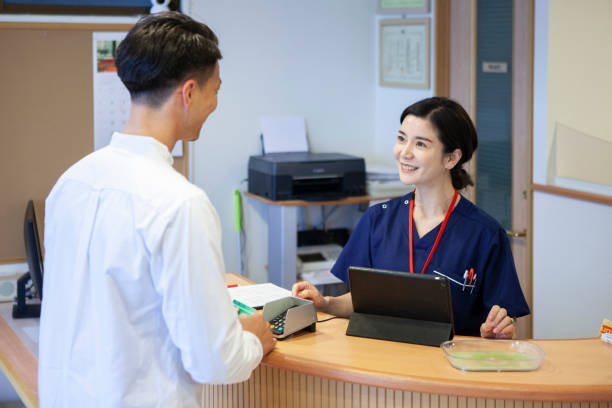 クリニック受付での男性患者会計 - 病院 ストックフォトと画像