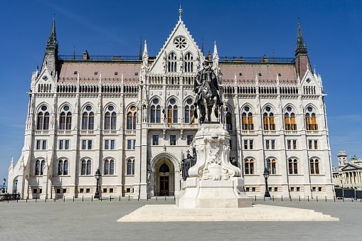 The image is a view of the Hungarian Parliament from the end of the building with a statue of an Hungarian statesman in the foreground