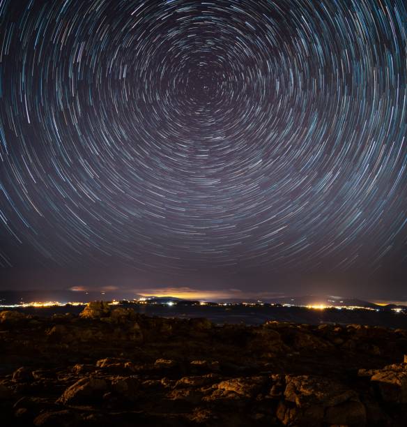 istock Town surrounded by lights in the evening under a starry sky with long exposure 1437204282