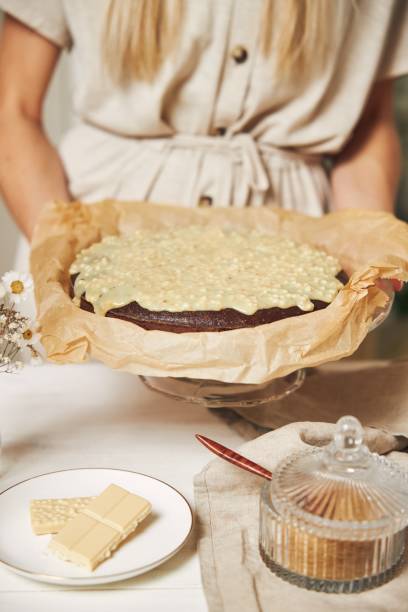istock Young female cook making a delicious chocolate cake with cream on a white table 1437204339
