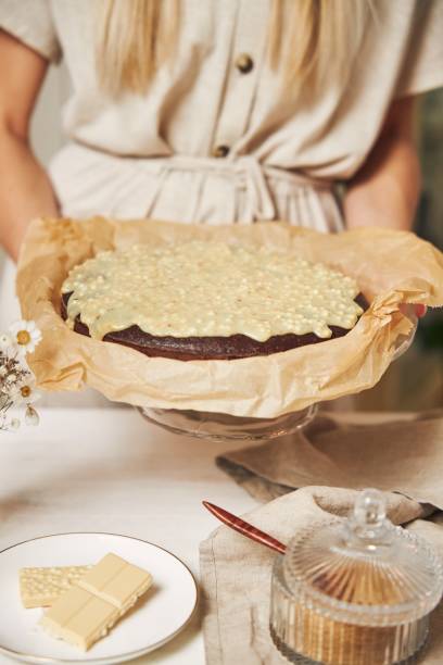 istock Young female cook making a delicious chocolate cake with cream on a white table 1437204362