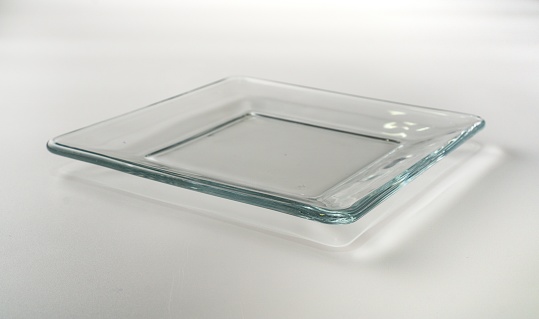 A closeup shot of a transparent glass plate on a gray background