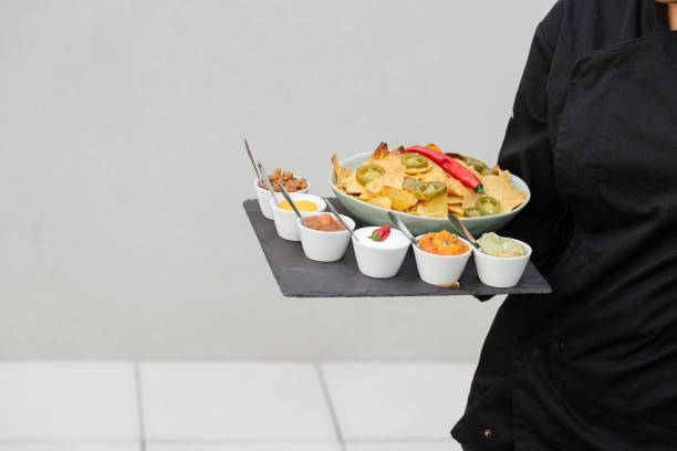 istock Waiter holding a plate with nachos and different sauces 1437204688