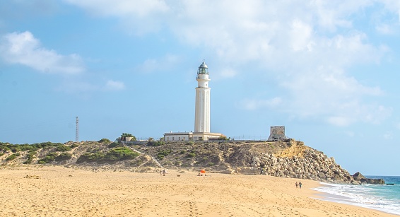A sunny scenery of a white lighthouse in a sandy beach