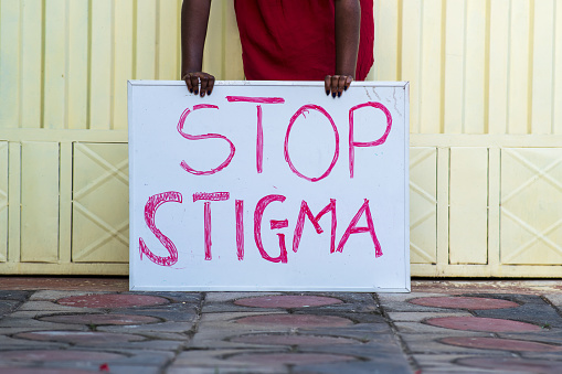 A black person holding a sign with text 