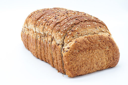 A loaf of irish wheaten bread on white background. The bread is sliced with a knife.