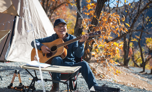 Man camping on the mountains singing and playing guitar.
