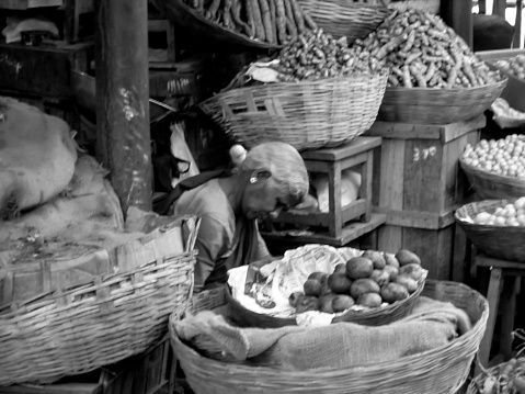 Mysore, India - nov 10, 2005: at the market in Mysore an elderly woman waits for customers at her vegetable stand. Black and white photo