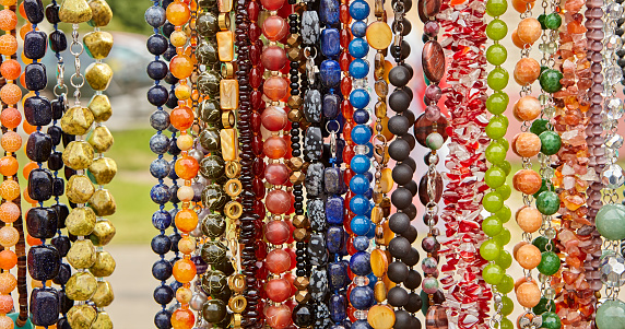Beads and necklaces made of colored semi-precious stones. Background of many beautiful jewelry, multi-colored turquoise stones, amber, cat's eye, pearls.