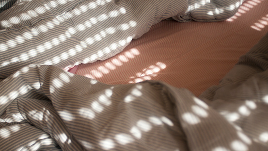 Morning lights through blinds in bed