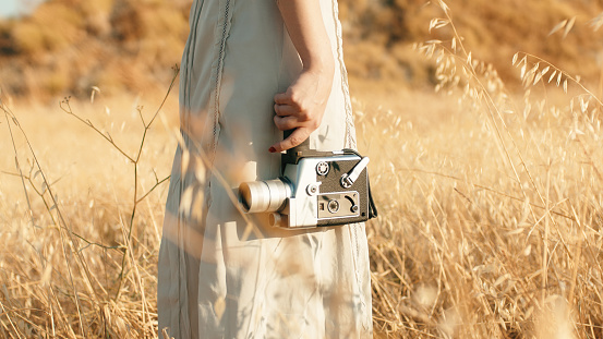 Beautiful girl in the countryside in summer with vintage 8mm camera.