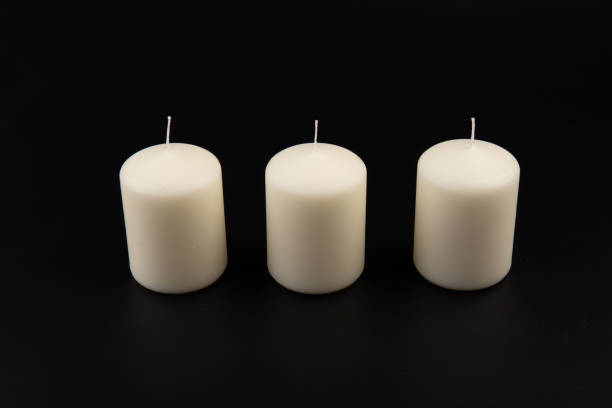istock White candles on dark background. Close-up, copy space. 1437216042