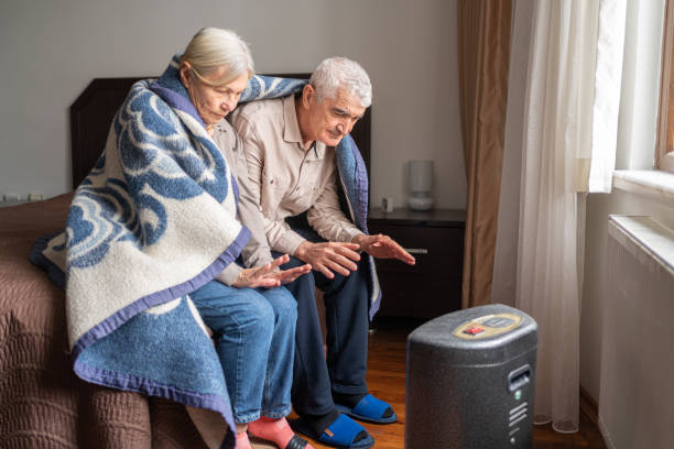 seniorenpaar wärmt ihre hände auf elektrische heizung zu hause.
energiekrise stock photo - women poverty senior adult mature adult stock-fotos und bilder