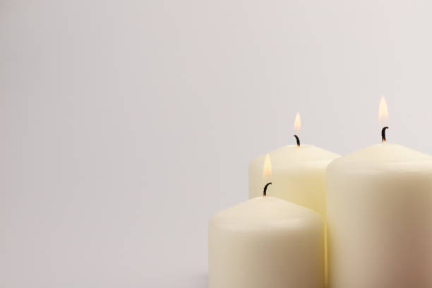 istock Burning white wax candles on white background. 1437216194