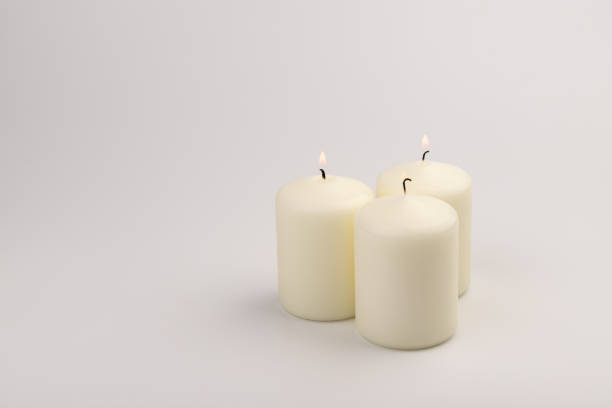 istock Burning white wax candles on white background. 1437216195