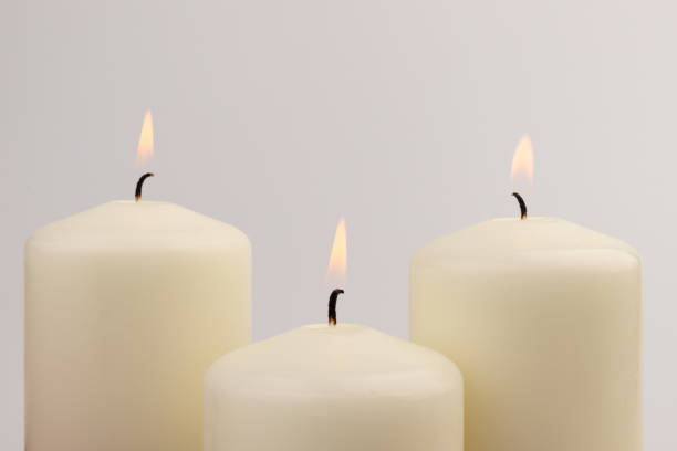 istock Burning white wax candles on white background. 1437216203