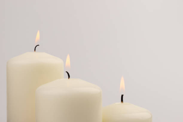 istock Burning white wax candles on white background. 1437216210